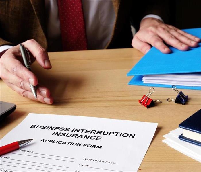 Business interruption insurance form and red pen for signing.