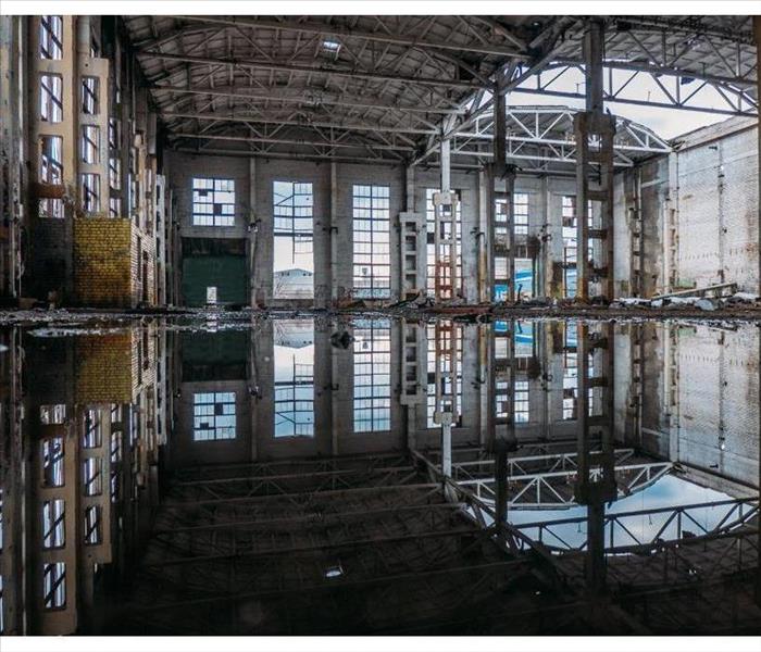 Inside of flooded dirty abandoned ruined industrial building with water reflection of interior.